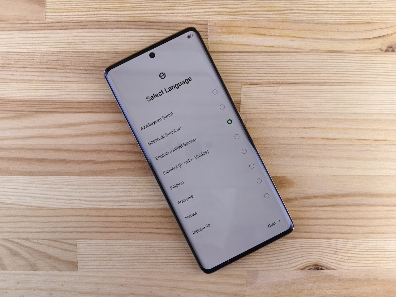 Close-up of smartphone with language selection screen on wooden table.